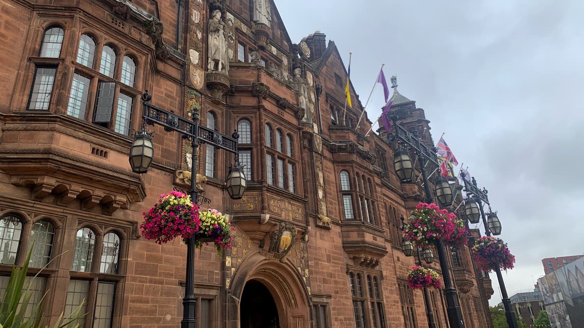 The red sandstone facade of Coventry Council House with hanging flower baskets