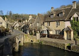 Honey-coloured stone cottages beside a brook in a Cotswolds village